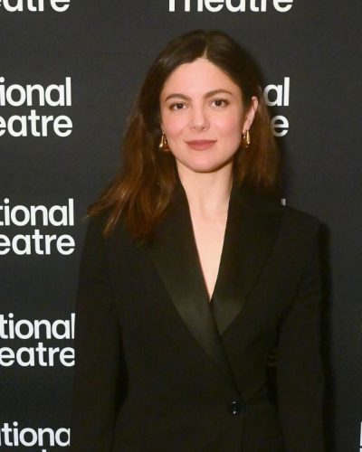 Monica Barbaro with a chic black blazer and flowing hairstyle.