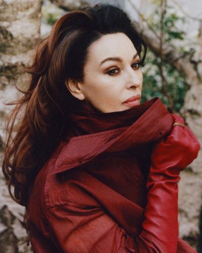 Monica Bellucci in a fitted beige dress with voluminous sleeves.