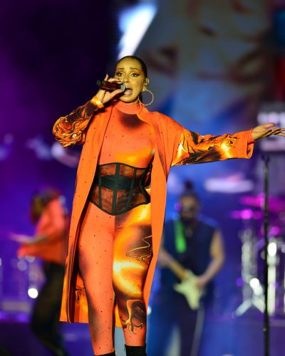 Mya in eye-catching orange jumpsuit with dynamic graphic coat