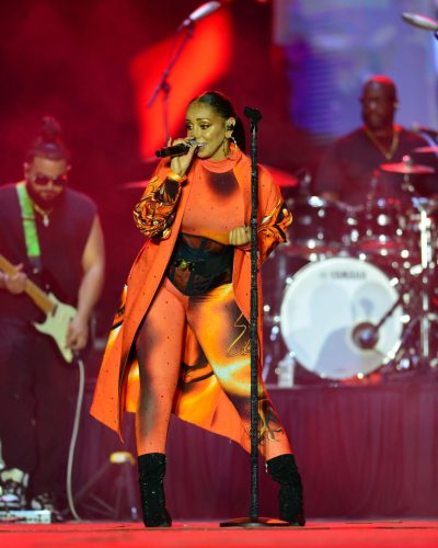 Mya in vibrant orange jumpsuit with shimmering details