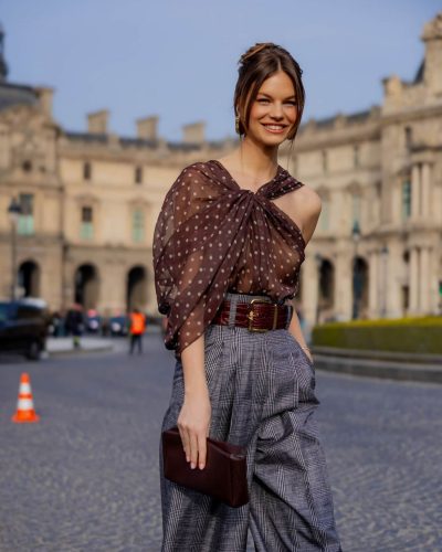 Nadine Leopold in brown polka dot sheer blouse and statement belt