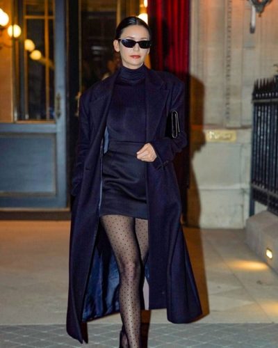 Nina Dobrev black trench coat contrasting with Parisian backdrop