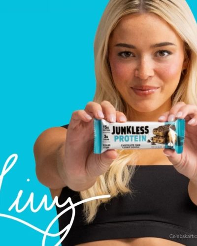 Olivia Dunne in white robe holding Junkless Foods protein bar