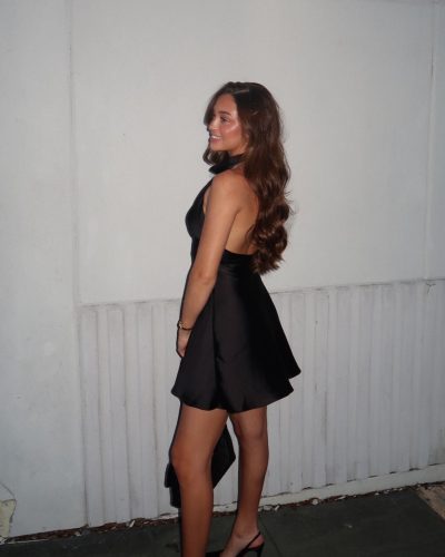 Presley Elise in a timeless black dress against a neutral backdrop.