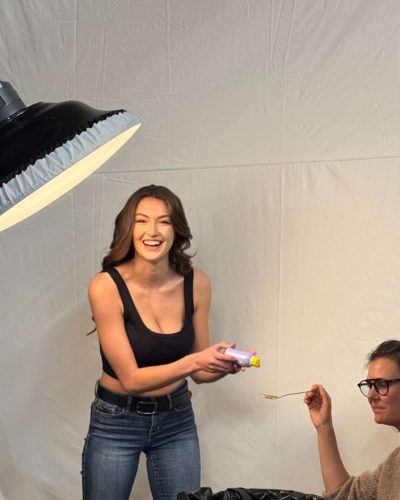 Rachel Pizzolato gray dress with sheer sleeves and striking red pillow