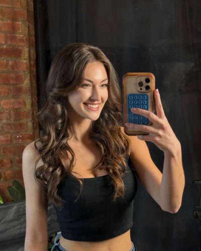 Rachel Pizzolato gray dress and black boots against lush greenery backdrop