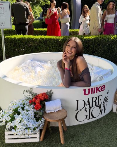 Rachel Pizzolato gray dress with sheer sleeves and striking red pillow