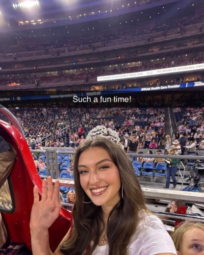 Rachel Pizzolato gray dress with sheer sleeves and striking red pillow