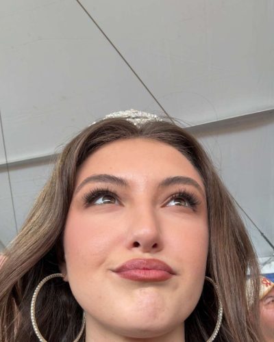 Rachel Pizzolato fashionable gray dress with black boots and red pillow