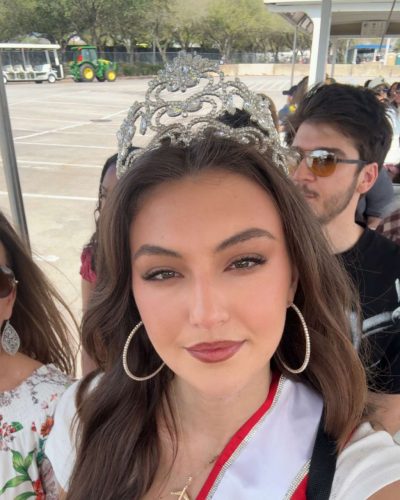 Rachel Pizzolato chic gray dress featuring sheer sleeves and red pillow