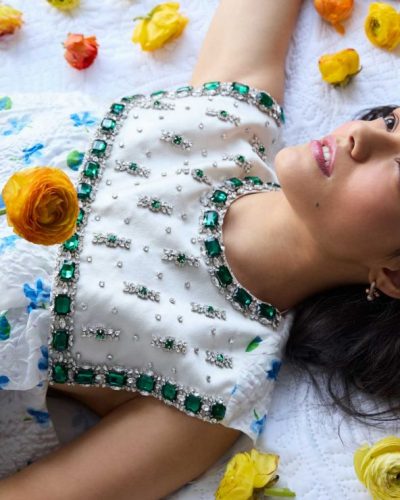 Rachel Zegler light backdrop accentuating red ruffled dress