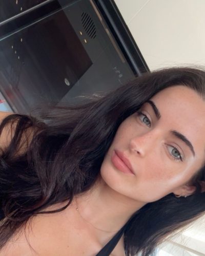 Renee Murden wearing yellow bikini with ocean waves behind.