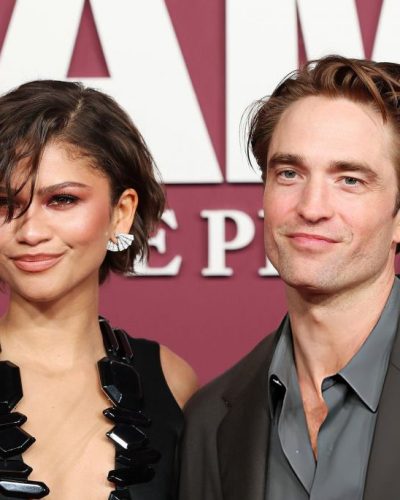 Robert Pattinson sporting a tailored black jacket and casual blue shirt.