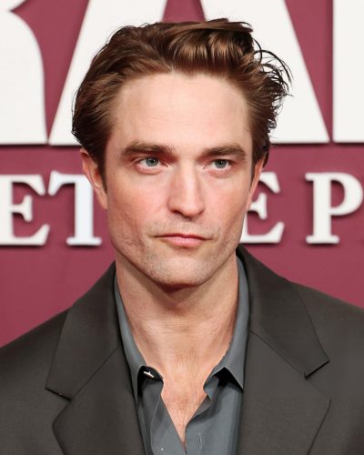 Robert Pattinson dressed in a fitted dark suit and casual shirt.