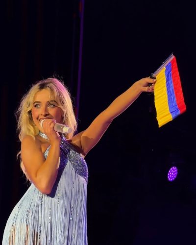 Sabrina Carpenter in vibrant blue jumpsuit with swaying fringe accents.