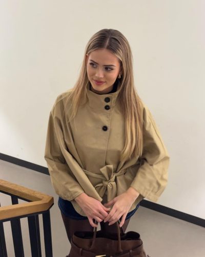 Sara Crumbleleg styled in minimalist beige trench coat and black top.