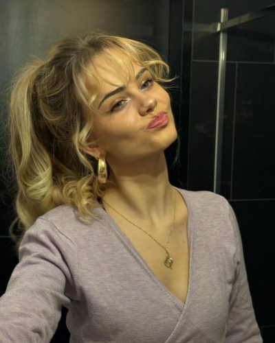 Sara Crumbleleg with structured brown handbag and black top.