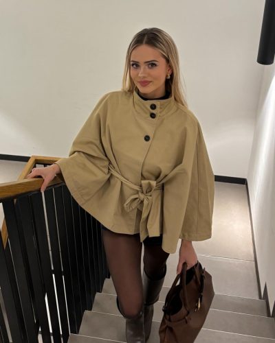 Sara Crumbleleg in fitted black top and chic beige outerwear.