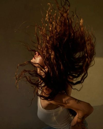 Sarah Shahi wearing distressed blue jeans and a white tank top