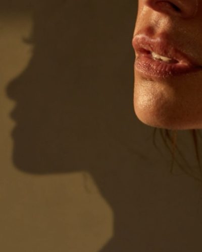 Sarah Shahi in relaxed white tank top and edgy blue jeans