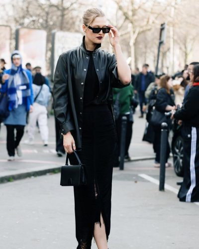 Toni Garrn sporting black leather coat over fitted black attire.