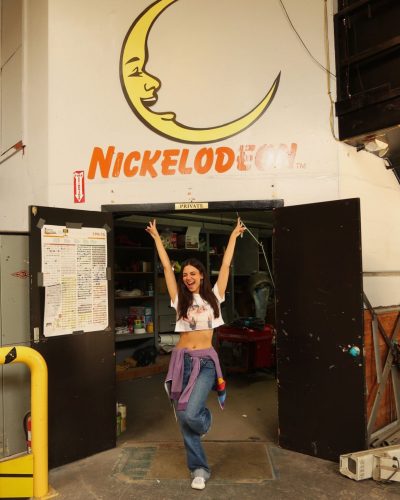 Victoria Justice wearing a purple wrap with a cropped graphic top.